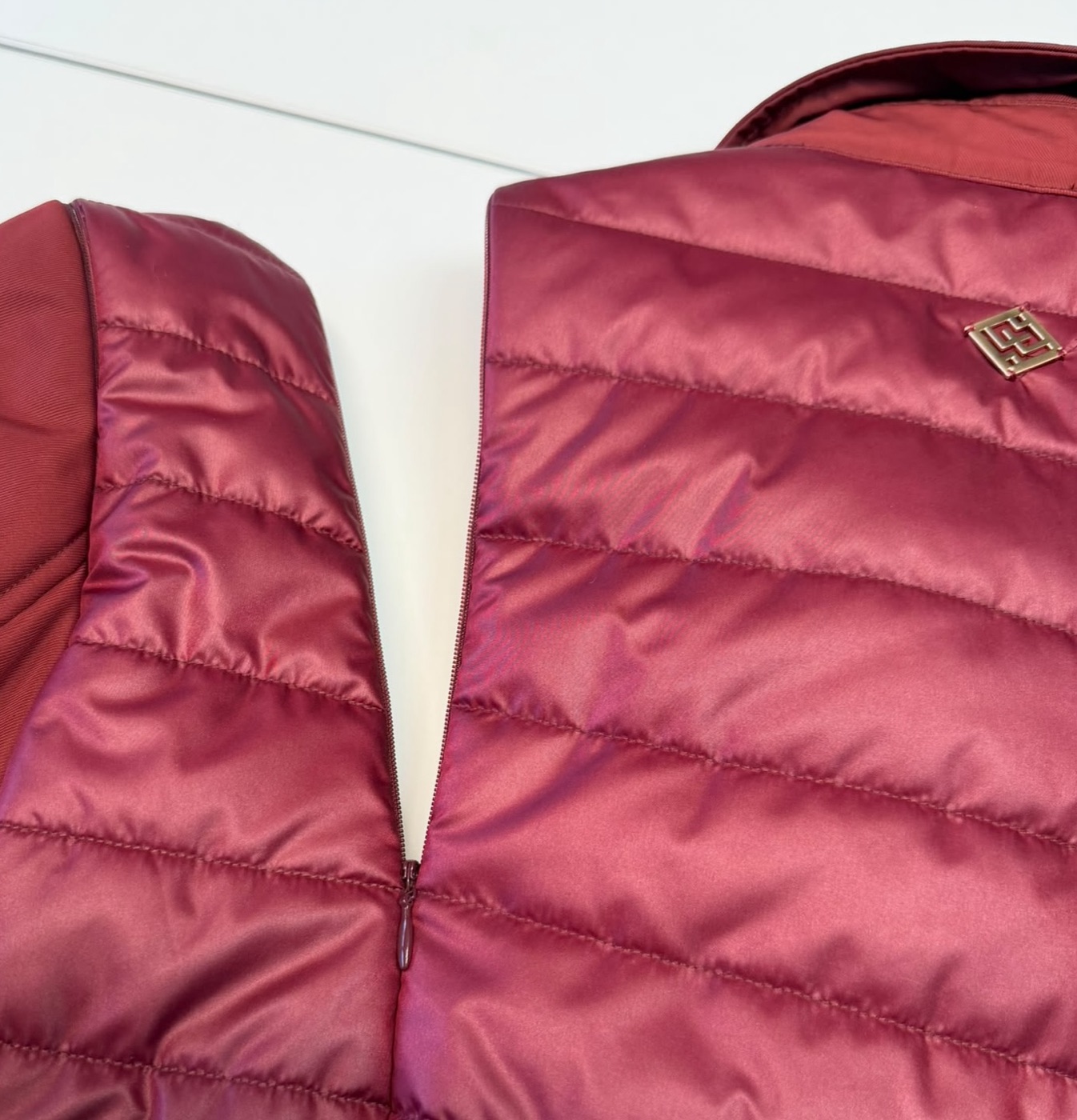 Dettaglio macro della cerniera invisibile Modular Wear: due pannelli trapuntati uniti dalla zip, con cursore in metallo e logo applicato